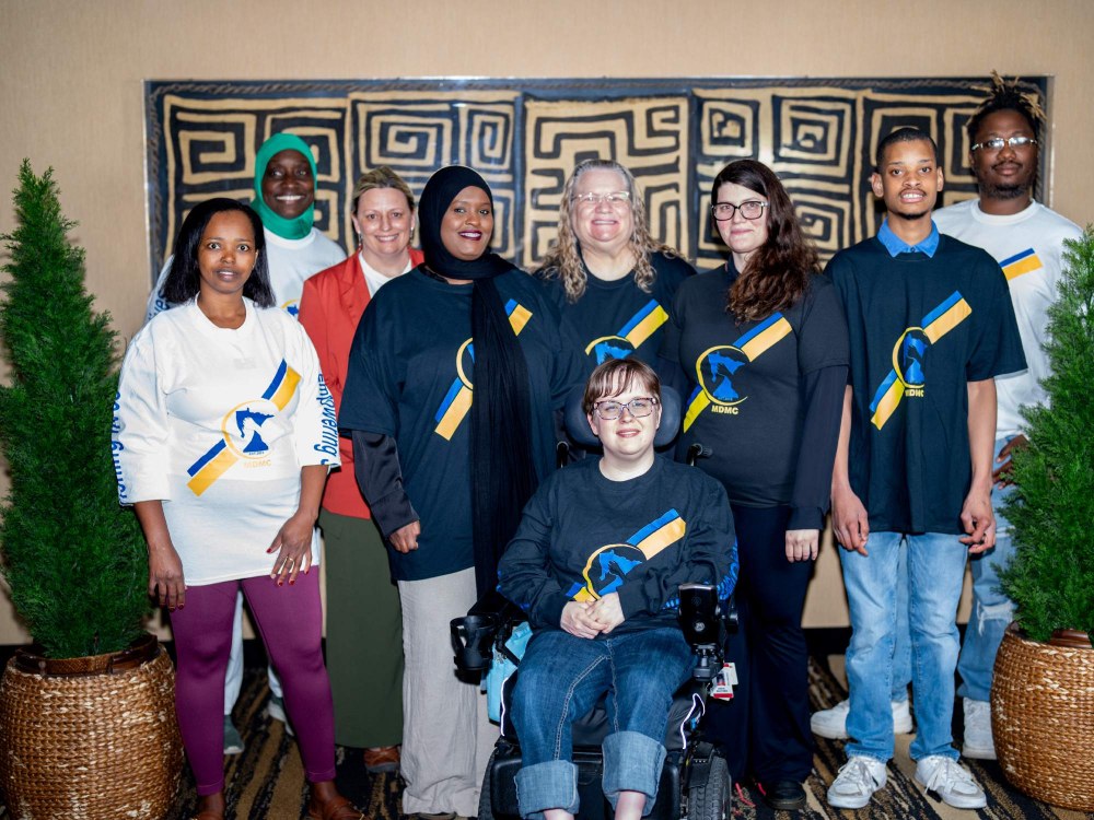 9 individuals standing side by side. Individuals include mixture of board and staff members.