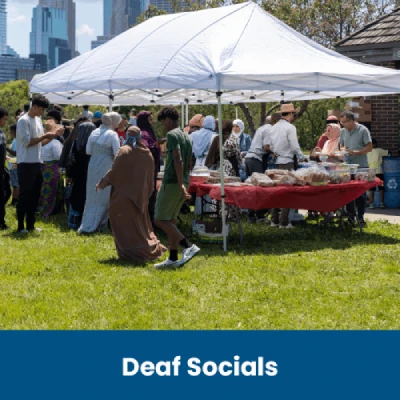Group of Pople enjoying social event at a park around a white tent