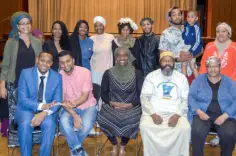 Several individuals stand together, smiling for a photo with a stage backdrop featuring colorful lights.